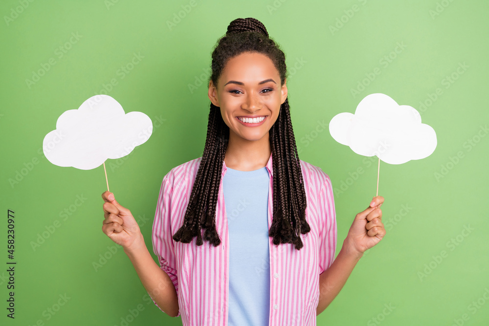 Photo of young happy positive dark skin woman hold hands clouds sticks isolated on green color background Photo of young happy positive dark skin woman hold hands clouds sticks isolated on green color background