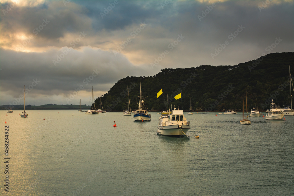 Sunset light reflected in calm waters of a small harbour. Fishing and sailing boats anchored near the coastrline. Sunset on a stormy day