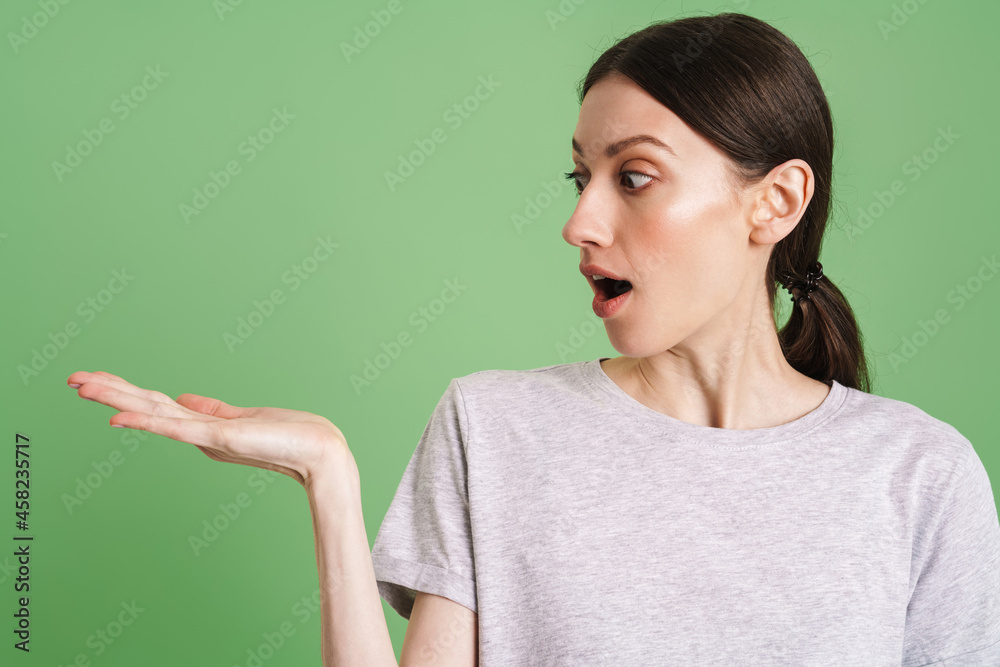 Young shocked woman holding and looking at copyspace Young shocked woman holding and looking at copyspace