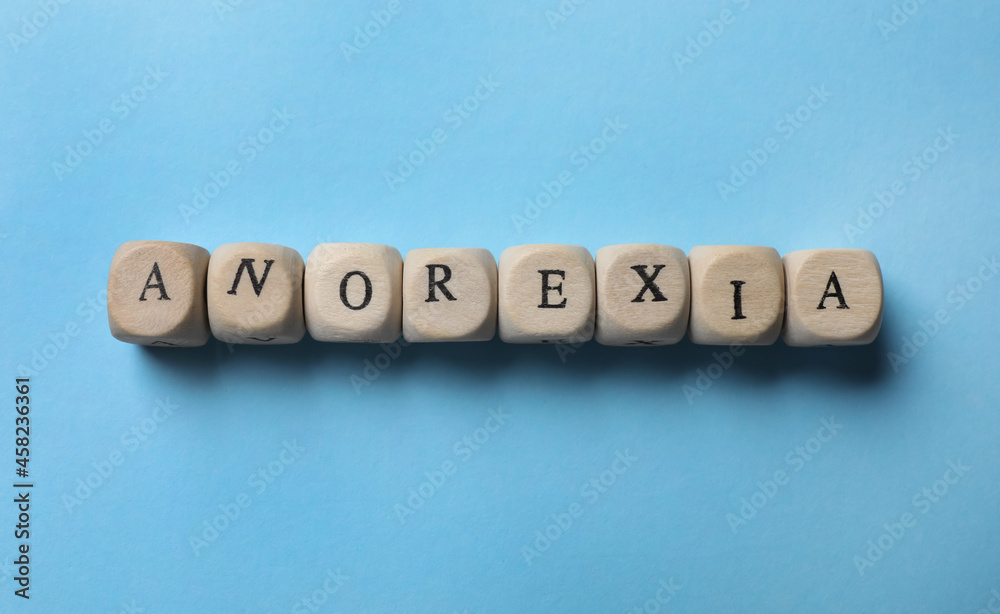 Word Anorexia made of wooden cubes on light blue background, flat lay Word Anorexia made of wooden cubes on light blue background, flat lay
