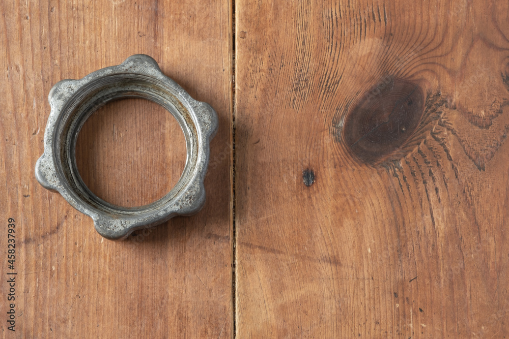 Union nut from an old aluminum home manual meat grinder on a wooden table. Parts of an old mechanical meat grinder. View from above. Union nut from an old aluminum home manual meat grinder on a wooden table. Parts of an old mechanical meat grinder. View from above.