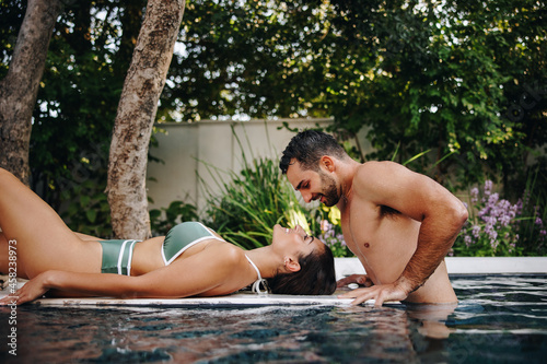 Honeymooners flirting at a luxury swimming pool photo