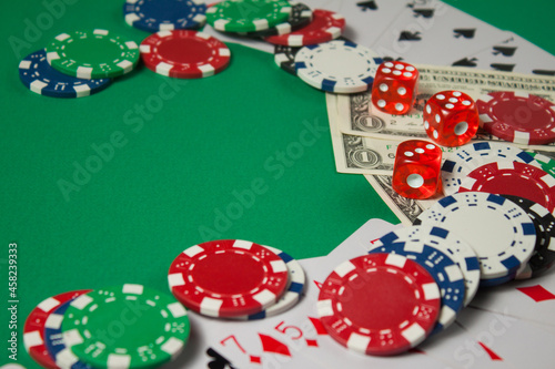 Classic playing cards, chips, red dice and dollars on green background with place for text. Gambling and casino concept.