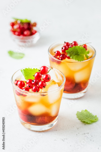 Red currants, strawberry summer refreshing cocktails, berry iced tea in glasses. Space fot text.