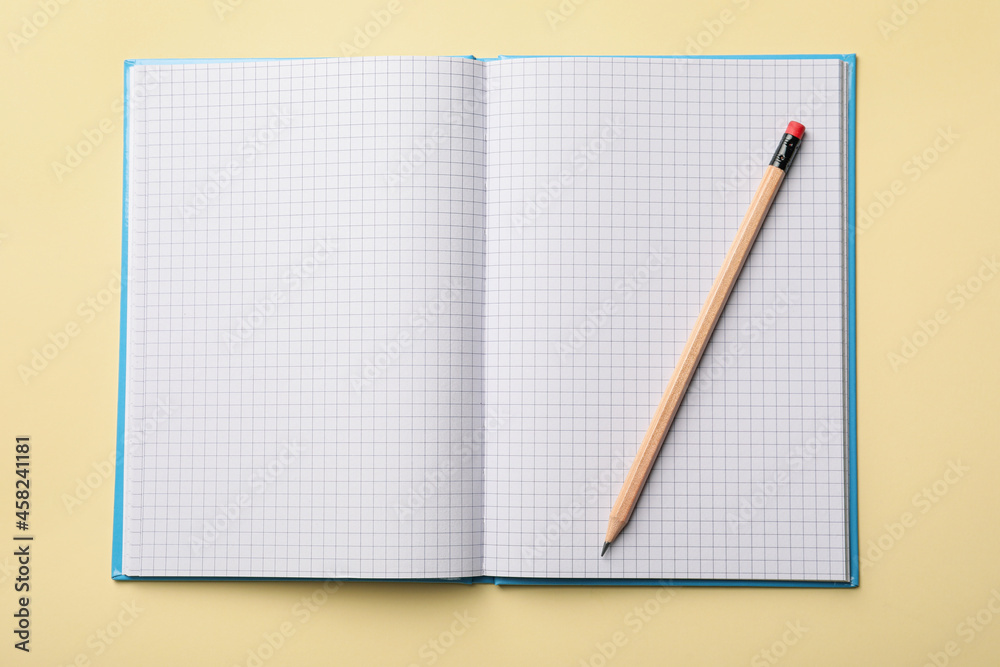 Open notebook with blank sheets and pencil on beige background, top view Open notebook with blank sheets and pencil on beige background, top view