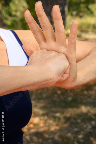 Athletic woman doing yoga in summer park. Woman's hands. 