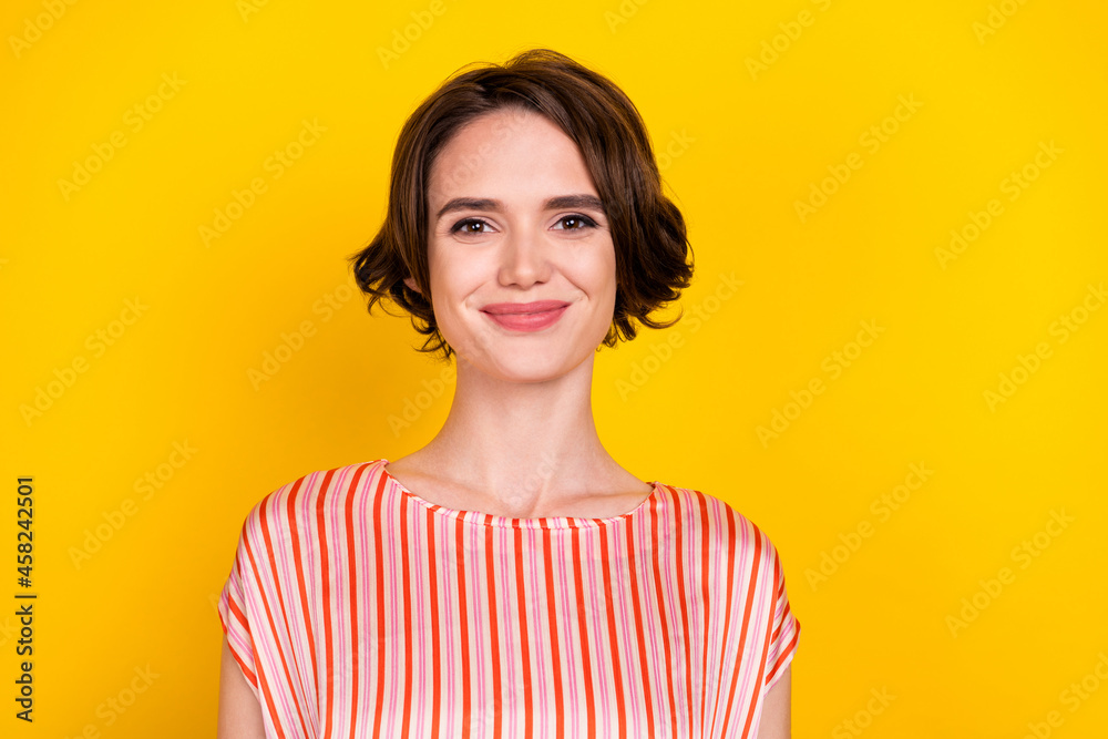Portrait of attractive cheerful brown-haired girl wearing striped blouse isolated over bright yellow color background Portrait of attractive cheerful brown-haired girl wearing striped blouse isolated over bright yellow color background