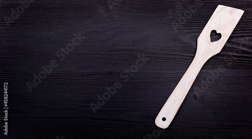 wooden spoon with a heart on a black wood background