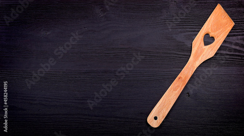 wooden spoon with a heart on a black wood background