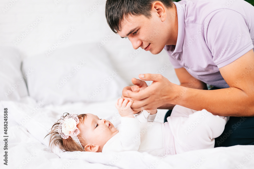 a newborn girl is lying with her young father in a snow-white bed. the concept of the family a newborn girl is lying with her young father in a snow-white bed. the concept of the family