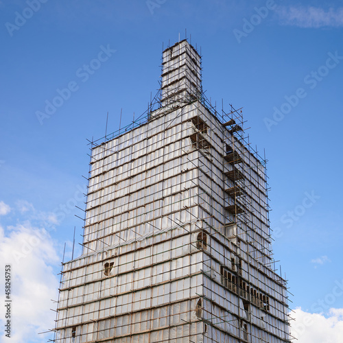 Scaffolding from planks around old bell tower. Concept of historical reenactment of repair work, access to elements of buildings of complex configuration.