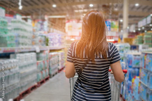 Woman shopping at supermarket with blur store background 