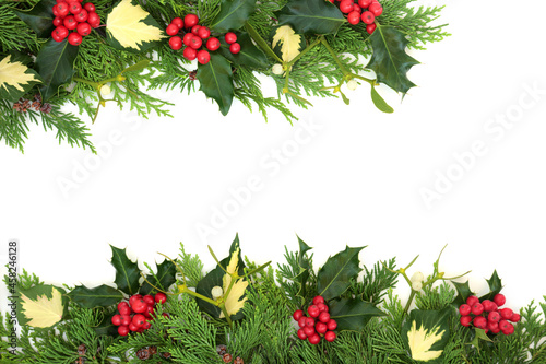 Traditional winter solstice  Christmas and New Year background border on white with holly  cedar  ivy and mistletoe.  Flat lay  top view  copy space.