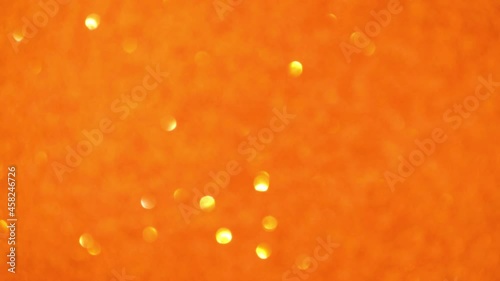 Abstract orange glitter background with moving and flicker particles. Magic dust, shiny texture and holiday lights, flying particles with beautiful bokeh. Shining christmas backdrop