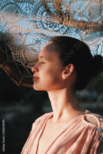 Close up portrait of young woman on the big lace dream catcher background. Boho model. Lace shadows portrait. Lace pattern portrait.
