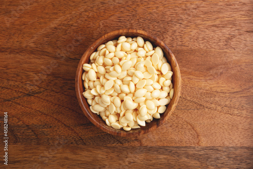 Wooden bowl of wax beans on wooden background. Top view. Hair removal, depilation.