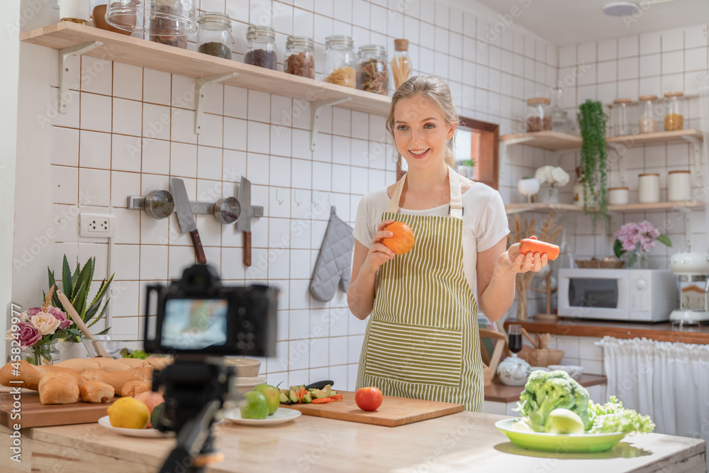 Young beautiful woman using camera recording video how to make a salad and making bakery for posting to social media in her channel food healthy at home kitchen Young beautiful woman using camera recording video how to make a salad and making bakery for posting to social media in her channel food healthy at home kitchen
