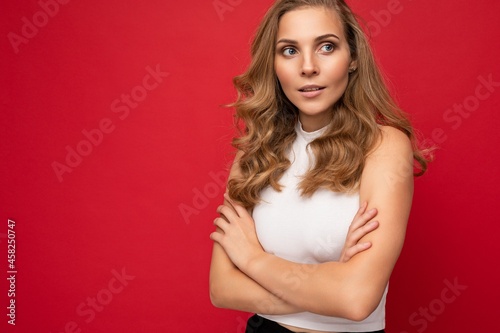 Portrait photo of adult beautiful pretty sexy positive self-confident blonde woman with sincere emotions wearing stylish white top isolated over red background with free space © Ivan Traimak