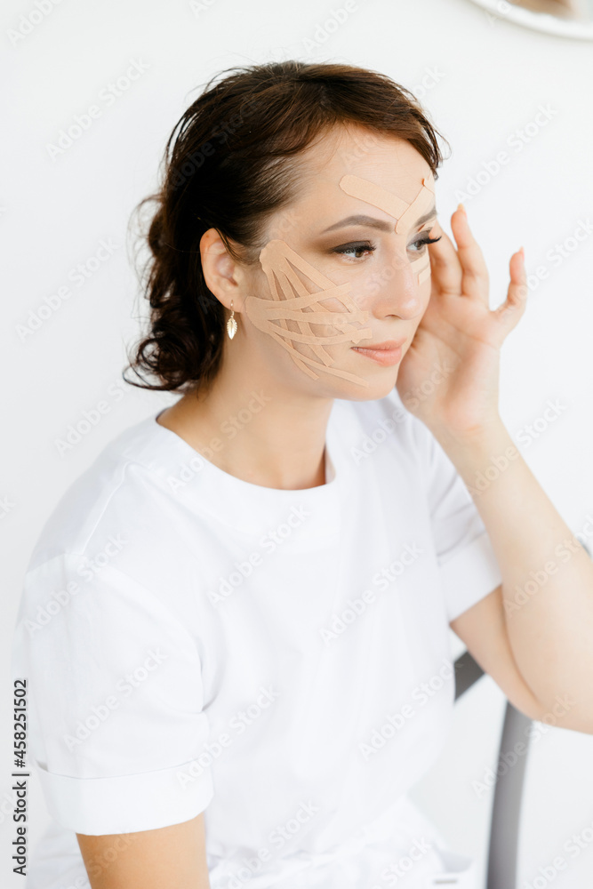 Portrait of a young Caucasian girl in a white coat with tapes on her face. she covers her face with duct tape. A young woman with ribbons on her face. An aesthetic patch for the face. a patch to maint Portrait of a young Caucasian girl in a white coat with tapes on her face. she covers her face with duct tape. A young woman with ribbons on her face. An aesthetic patch for the face. a patch to maint