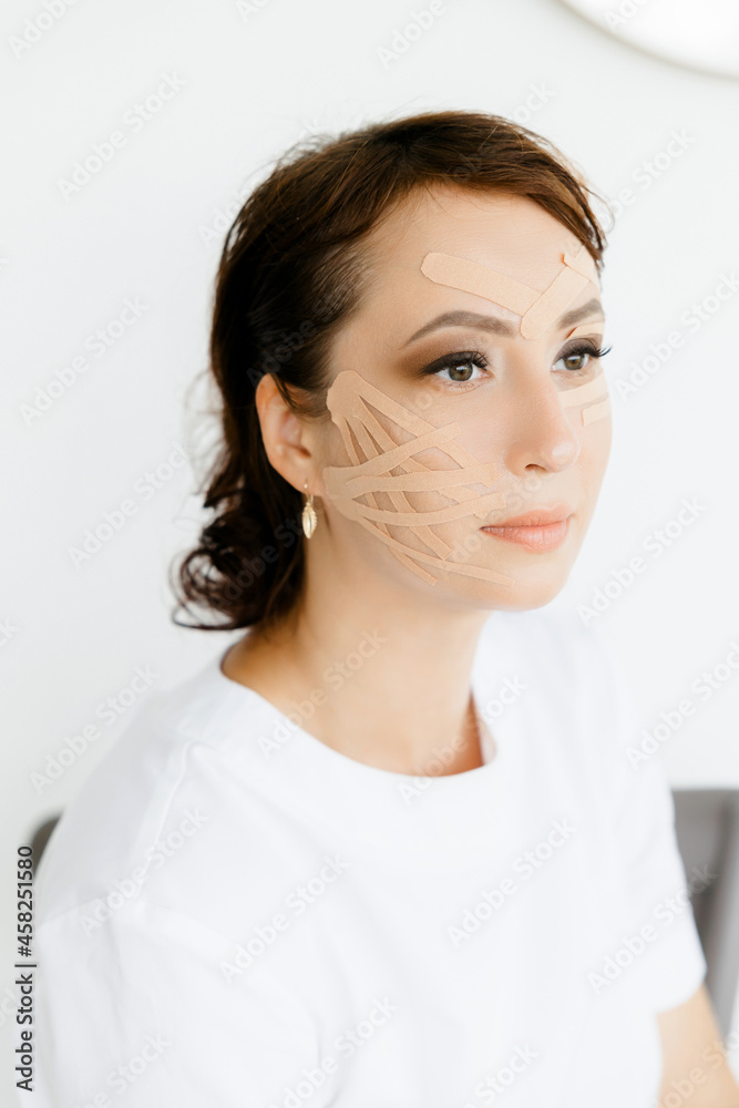Portrait of a young Caucasian girl in a white coat with tapes on her face. she covers her face with duct tape. A young woman with ribbons on her face. An aesthetic patch for the face. a patch to maint Portrait of a young Caucasian girl in a white coat with tapes on her face. she covers her face with duct tape. A young woman with ribbons on her face. An aesthetic patch for the face. a patch to maint