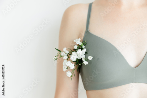a part of the girl's body. white flowers stick out of the armpit. the concept of cosmetology and body hair removal. Women's health and intimate hygiene.