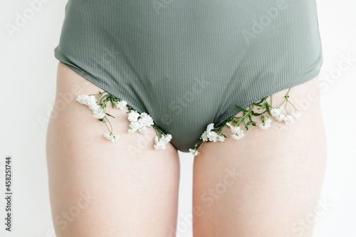 a part of the girl's body. white flowers stick out of his underpants. the concept of cosmetology and body hair removal. Women's health and intimate hygiene.