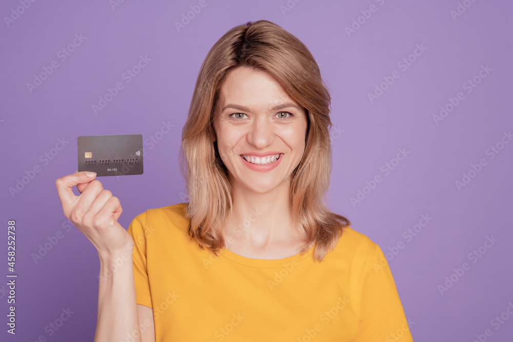Photo of young attractive woman happy positive smile show credit card salary isolated on violet color background Photo of young attractive woman happy positive smile show credit card salary isolated on violet color background
