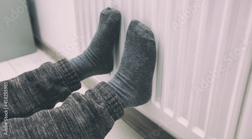 Boy warms legs near the radiator