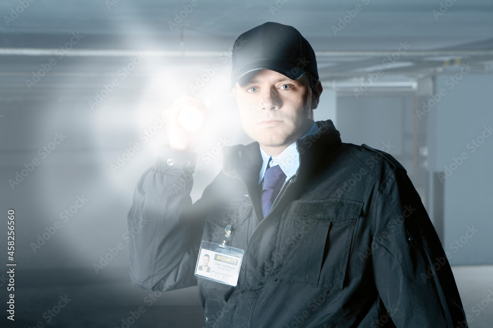 Security guard with flashlight at door in empty parking garage - obrazy, fototapety, plakaty 
