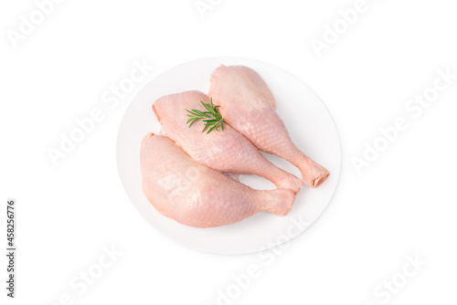 Three raw whole chicken legs on a white plate on a white isolated background. Fresh chicken legs.