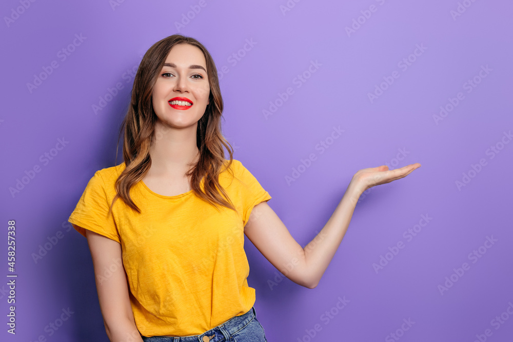 Young caucasian young woman smiling and pointing her finger at copy space isolated on lilac background in studio Young caucasian young woman smiling and pointing her finger at copy space isolated on lilac background in studio
