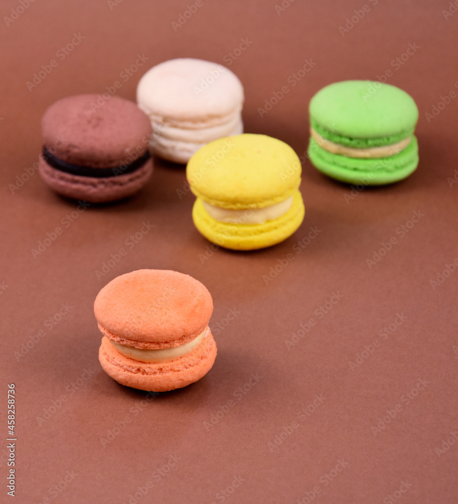 Fototapeta premium Colorful macarons on a brown background stock images. Colored french macarons isolated on a brown background with copy space for text