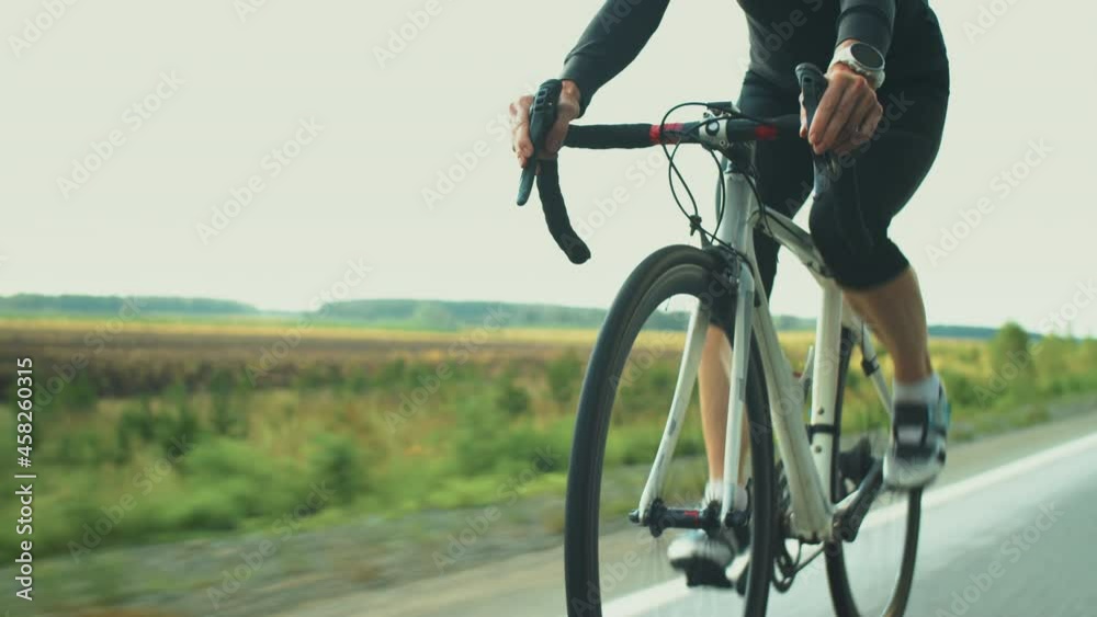 Professional female triathlete in protective helmet and sunglasses cycling on road while preparing for triathlon race Professional female triathlete in protective helmet and sunglasses cycling on road while preparing for triathlon race