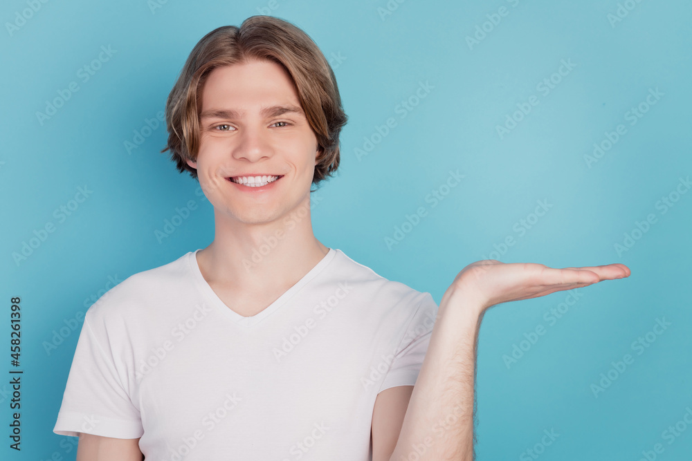 Photo of young guy show empty space promo isolated over blue background Photo of young guy show empty space promo isolated over blue background