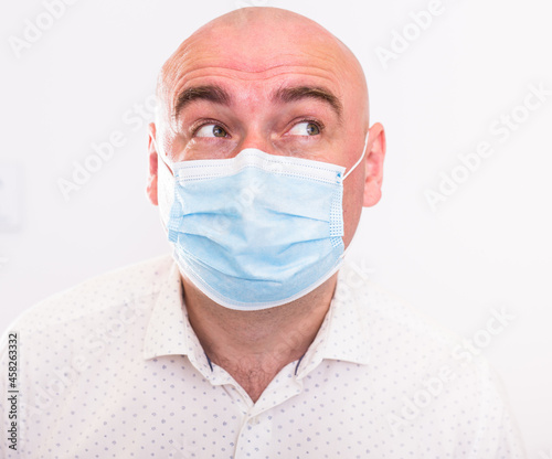 portrait of bald adult elderly man in medical mask with emotions on white background
