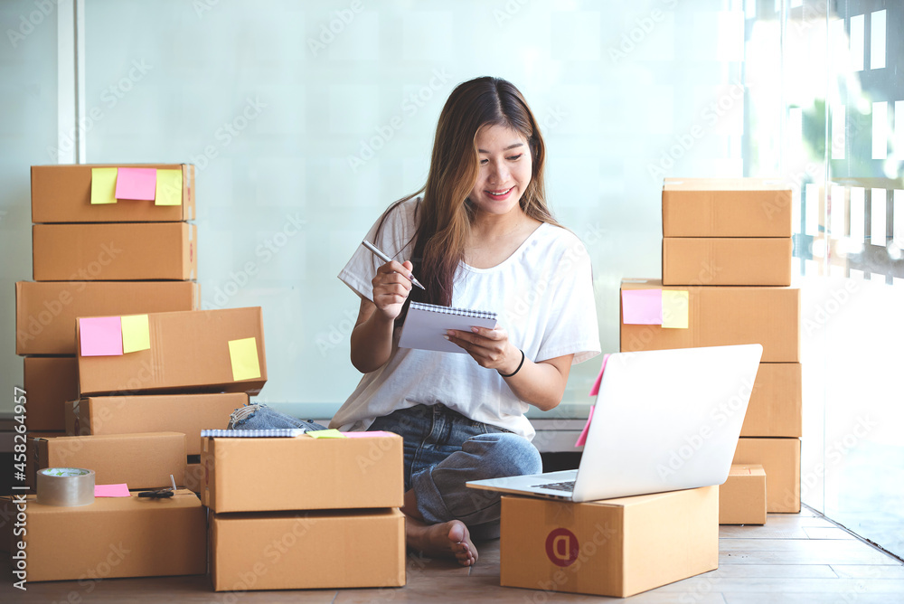 Small start-up business owners using computers at work, freelancers, saleswoman, checking production orders. Pack products for delivery to customers Small start-up business owners using computers at work, freelancers, saleswoman, checking production orders. Pack products for delivery to customers