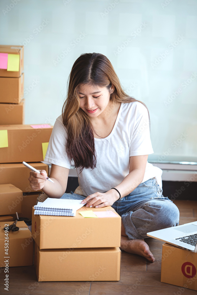 Small start-up business owners using computers at work, freelancers, saleswoman, checking production orders. Pack products for delivery to customers Small start-up business owners using computers at work, freelancers, saleswoman, checking production orders. Pack products for delivery to customers