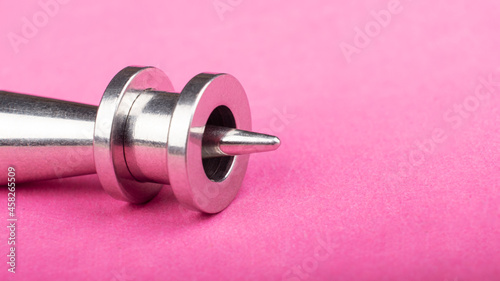 ear jewelry, tunnel and ear dilators on pink background close up. photo