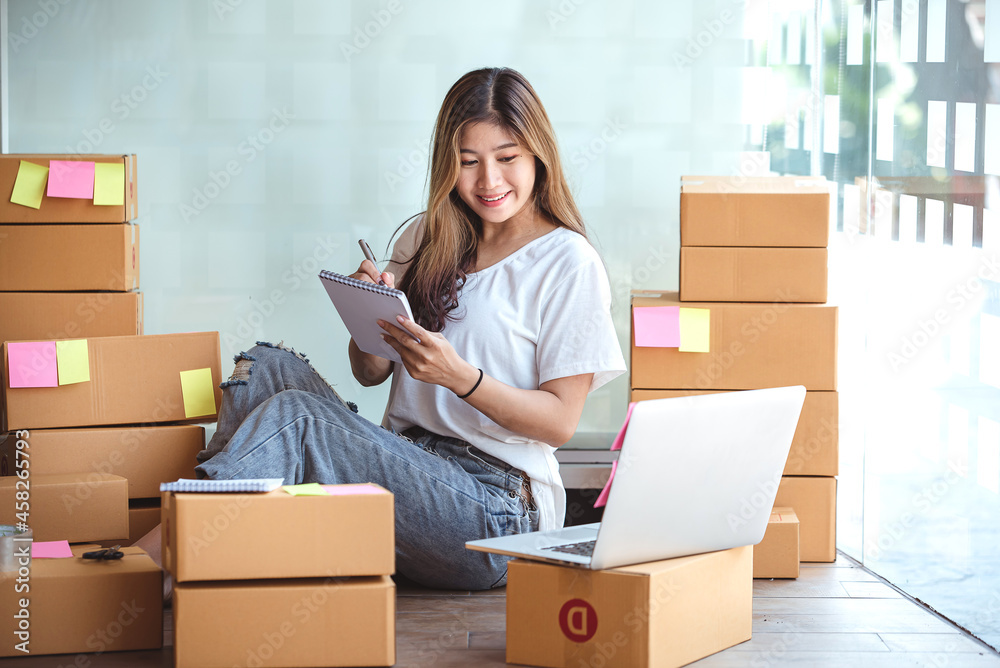 Small start-up business owners using computers at work, freelancers, saleswoman, checking production orders. Pack products for delivery to customers