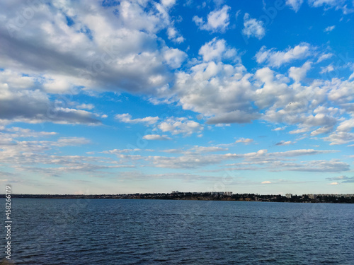 large river with blue water with waves and white clouds above the cliff