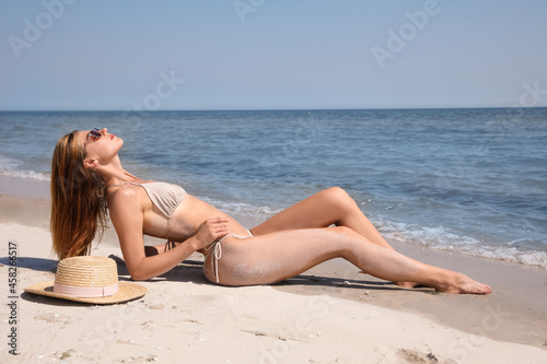 Attractive woman in bikini on sandy beach near sea