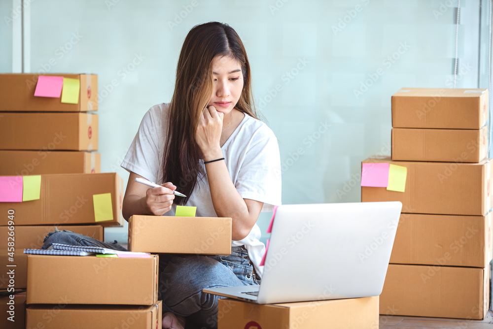 Small start-up business owners using computers at work, freelancers, saleswoman, checking production orders. Pack products for delivery to customers Small start-up business owners using computers at work, freelancers, saleswoman, checking production orders. Pack products for delivery to customers