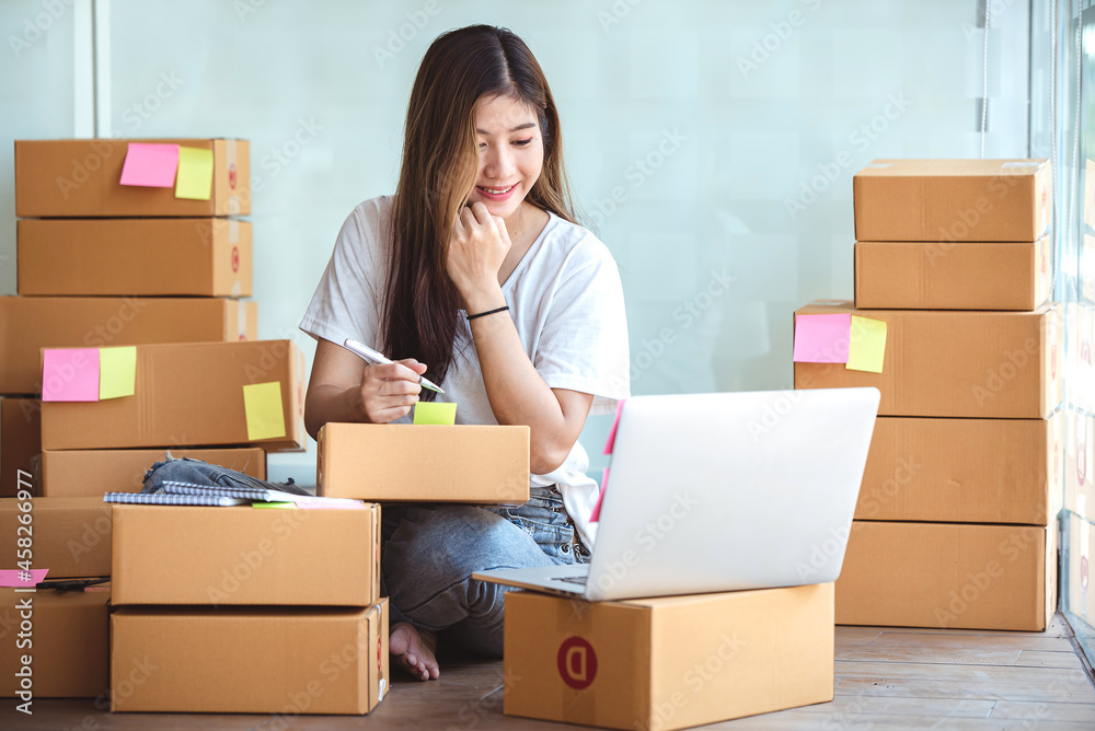 Small start-up business owners using computers at work, freelancers, saleswoman, checking production orders. Pack products for delivery to customers Small start-up business owners using computers at work, freelancers, saleswoman, checking production orders. Pack products for delivery to customers