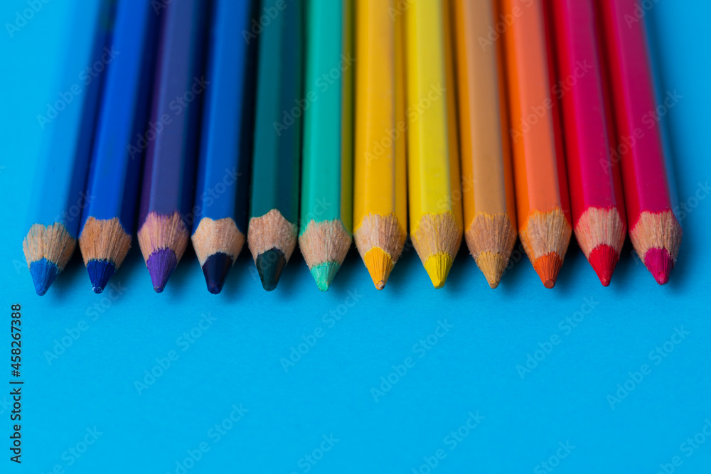Set of wooden colored pencils on a blue sheet of paper background Set of wooden colored pencils on a blue sheet of paper background