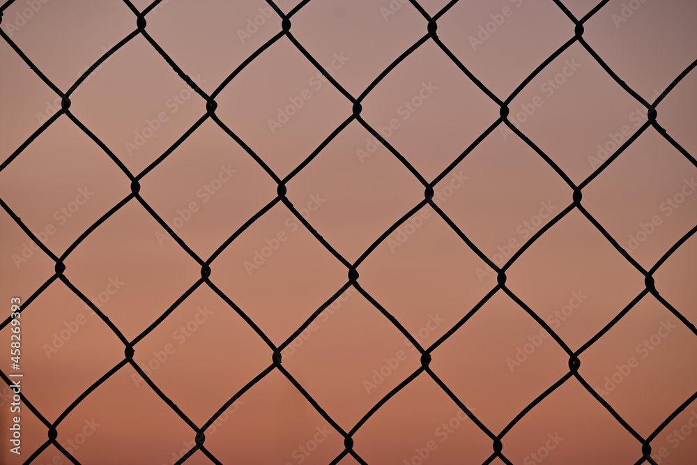 Naklejka premium Close-up of wire fence, sunset background, concept of freedom