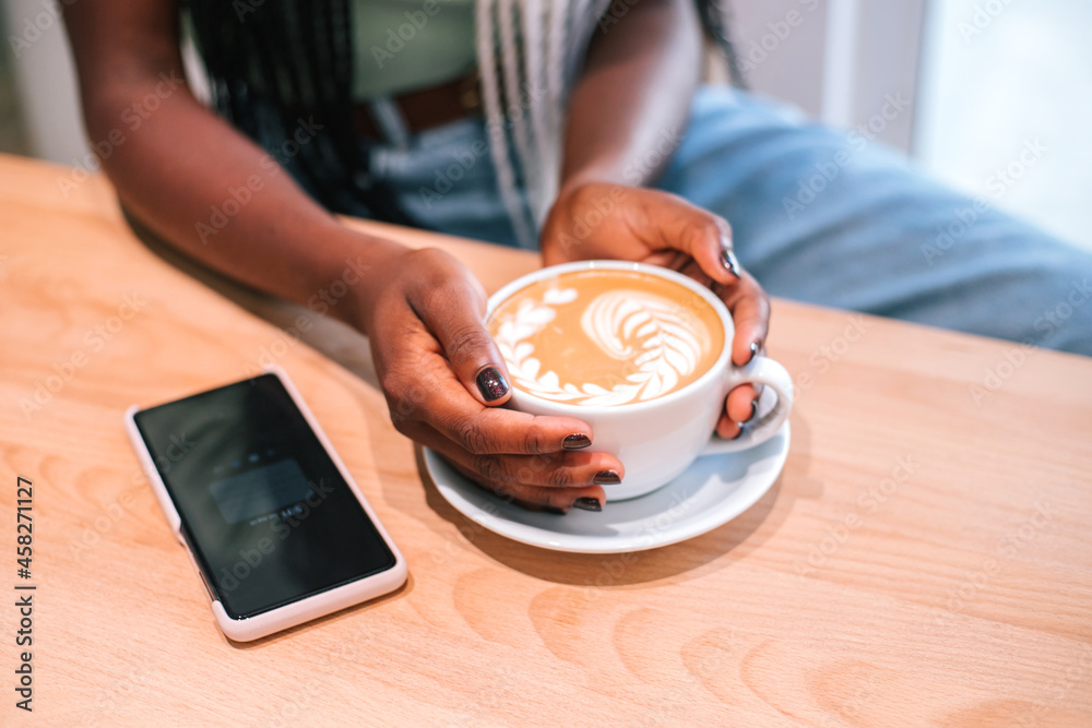 Young black girl listening to music on smartphone at cafe.