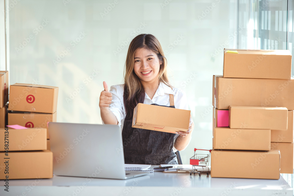 Small start-up business owners using computers at work, freelancers, saleswoman, checking production orders. Pack products for delivery to customers Small start-up business owners using computers at work, freelancers, saleswoman, checking production orders. Pack products for delivery to customers