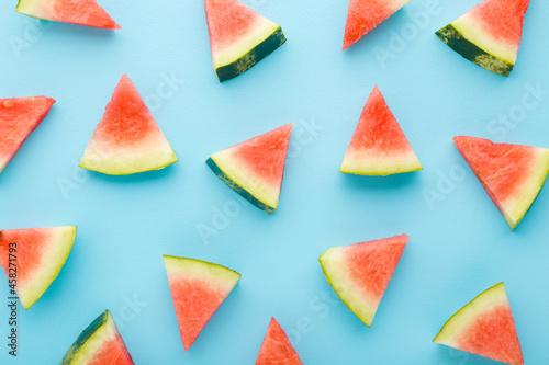 Beautiful fresh red pieces of watermelon on light blue table background. Pastel color. Closeup. Sweet food pattern. Top down view.