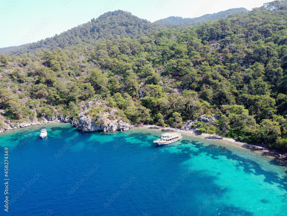 Aerial drone photo of yacht anchored in crystal clear bay and turquoise beach. uninhabited island in mediterranean sea. Place for swimming in sea while tourist boat trip