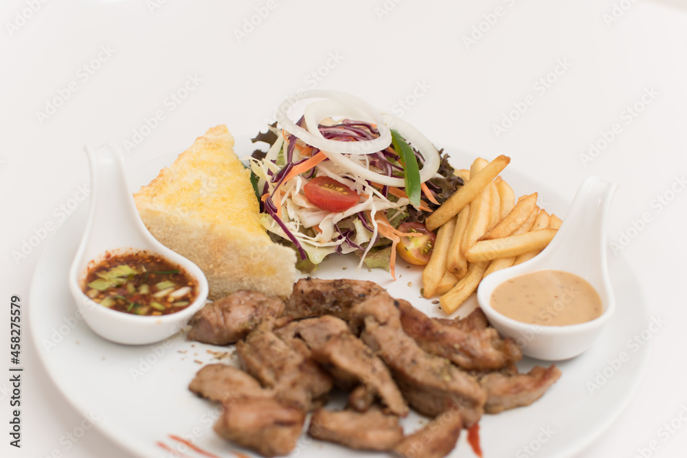 Steak platter with a side dish of bread, salad, sauce, french fries.